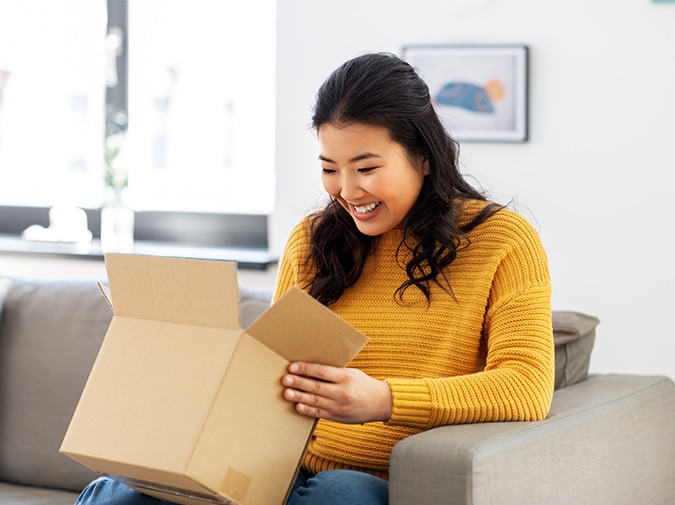 Excited woman opens delivery box with gift inside
