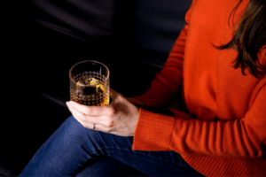 Woman holds cocktail after finishing holiday gifting
